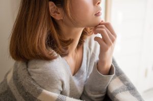 冬の日の窓辺で頬杖をつく女性